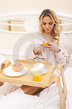 young beauty blond woman having breakfast in bed early sunny morning, princess house interior room, healthy lifestyle