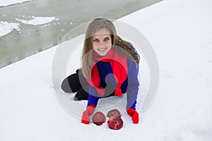 The young beauty the blonde placed red apples on snow.