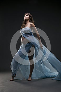 Young beauty and caucasian pregnant woman with blue silk on gray studio background