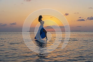 Young beauty girl dancing at tropical beach on sea water at paradise island at sunset. Summer concept