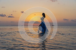 Young beauty girl dancing at tropical beach on sea water at paradise island at sunset. Summer concept