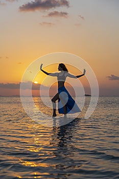 Young beauty girl dancing at tropical beach on sea water at paradise island at sunset. Summer concept