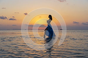 Young beauty girl dancing at tropical beach on sea water at paradise island at sunset. Summer concept