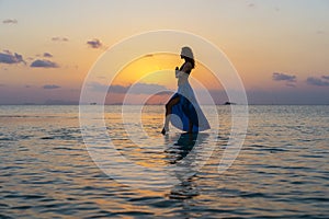 Young beauty girl dancing at tropical beach on sea water at paradise island at sunset. Summer concept. Holiday travel