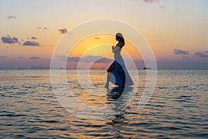 Young beauty girl dancing at tropical beach on sea water at paradise island at sunset. Summer concept. Holiday travel