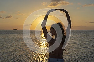 Young beauty girl dansing at tropical beach near sea water at paradise island at sunset. Summer concept. Holiday travel