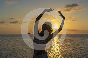 Young beauty girl dansing at tropical beach near sea water at paradise island at sunset. Summer concept. Holiday travel