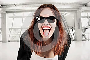 Young beauty hipster woman screaming and showing tongue, funny face with sunglasses