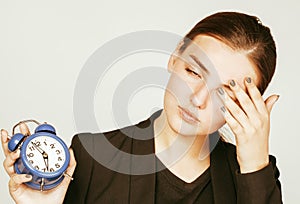 Young beauty woman in business style costume waking up for work early morning on white background with clock drinking