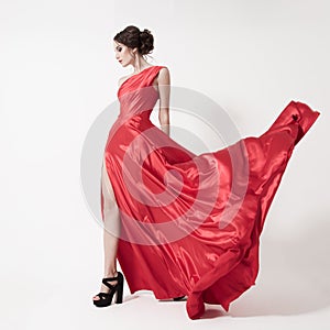 Young beauty woman in fluttering red dress. White background.