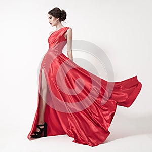 Young beauty woman in fluttering red dress. White background.