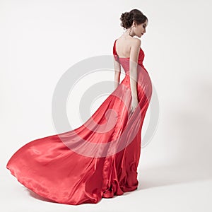 Young beauty woman in fluttering red dress. White background.