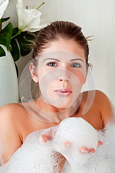 Young beauty woman in the full of foam bathtub