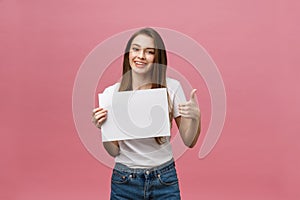 Young beauty woman hold blank card and showing thumbs up over pink background