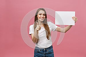 Young beauty woman hold blank card and showing thumbs up over pink background