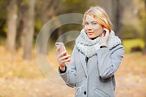 Young Beauty woman listening music in autumn forest