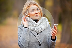 Young Beauty woman listening music in autumn park