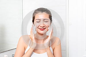 Young beauty woman washing her face in bathroom