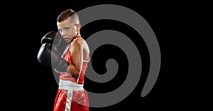 Young beginner boxer, sportive boy training isolated over dark background. Concept of sport, movement, studying