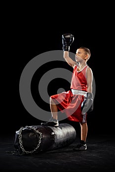 Young beginner boxer, sportive boy training isolated over dark background. Concept of sport, movement, studying