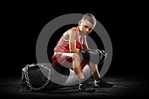 Young beginner boxer, sportive boy training isolated over dark background. Concept of sport, movement, studying