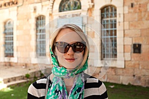 A young believing woman stands in a scarf near the entrance to a church in Jerusalem, Israel