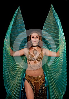 Young belly dancer posing with Isis wings