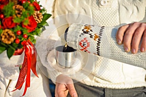 young beloved couple warming themselves in the winter park. hands with cups of hot tea.