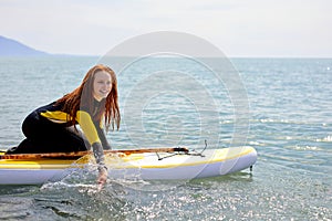 Young beuatiful redhead surfer woman making preparation for surf session