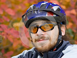 Young bicycler on the background of autumn leaves