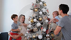 Young Big Family of Four Decorating Xmas Tree