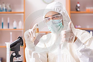 The young biochemist wearing protective suit working in the lab