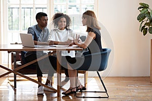 Young biracial couple consulting talking with female designer at meeting