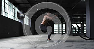 Young biracial man performs squats at a gym
