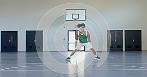 Young biracial man plays basketball in an indoor court