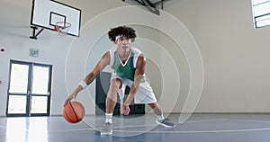 Young biracial man plays basketball indoors