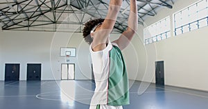 Young biracial man practices basketball in an indoor court