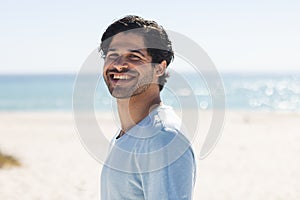 A young biracial man smiles brightly at the beach