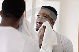Young biracial man wash wipe face in home bathroom