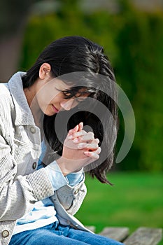 Young biracial teen girl praying outdoors