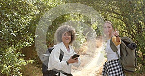 Young biracial woman with curly hair and a young Caucasian woman with blonde hair are hiking