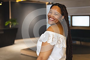 A young biracial woman is smiling in a modern business office with copy space