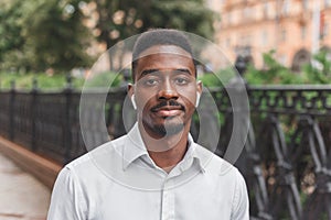 Young black african man in city face portrait with wireless earbuds