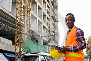 Young black African man construction worker holding clipboard an