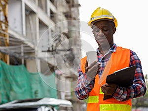 Young black African man construction worker holding clipboard wh