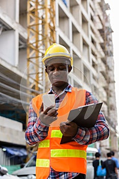 Young black African man construction worker holding clipboard wh