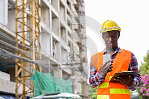 Young black African man construction worker reading on clipboard