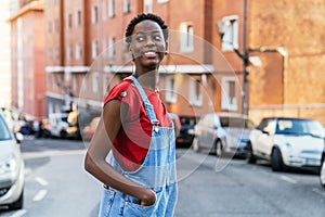 Young black African model woman crossing the street of a city very smiling.