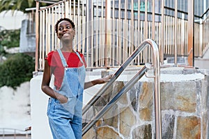 Young black African woman very cheerful and smiling walking up the stairs of a city.