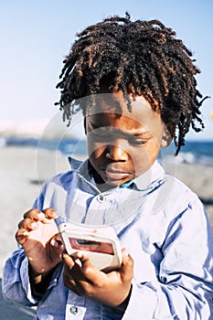 Young black afro children use modern cellular phone with internet games connection - addiction and modern people with technology